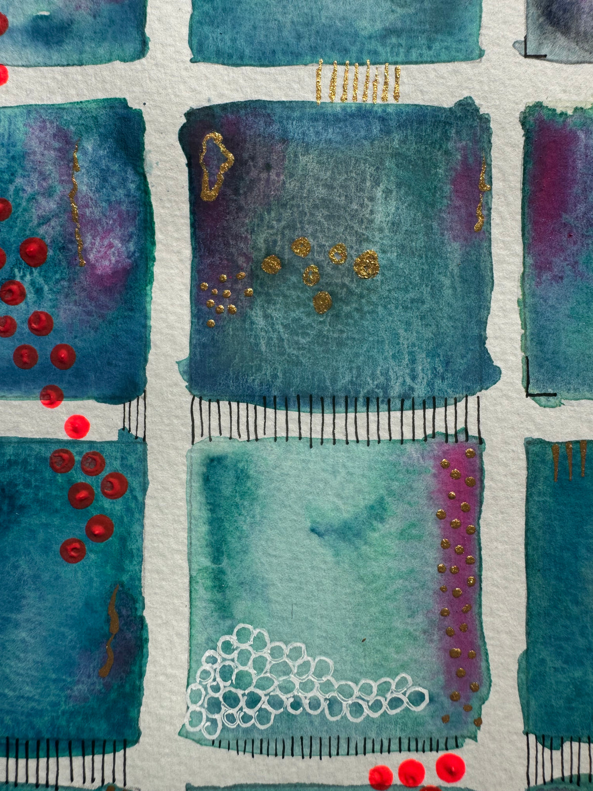 Close-up of teal squares with red dots and black stitched lines.